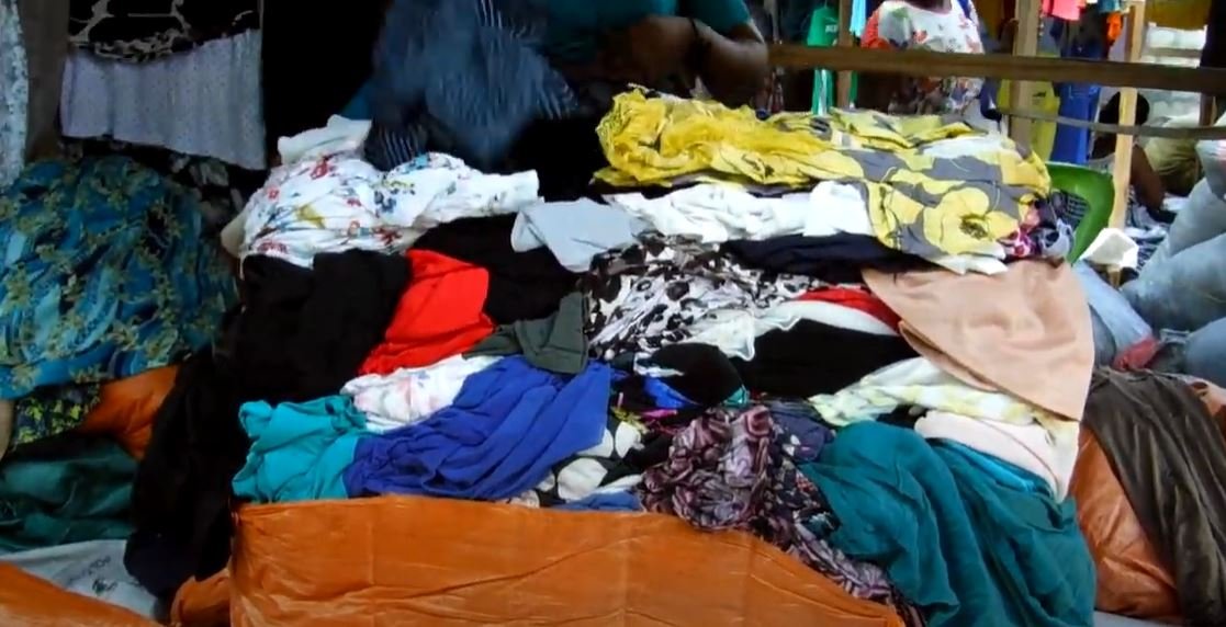 Screenshot of a still from the Dead White Man's Clothes Trailer on YouTube. Image shows a pile of clothes.