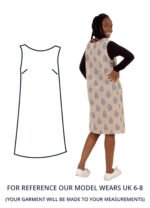 Our model Michiel with their back turned to us wearing a cream patterned shift dress with black long sleeves underneath.